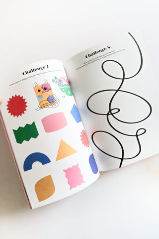 A books open to pages with colorful shapes and a black line drawing on a white surface