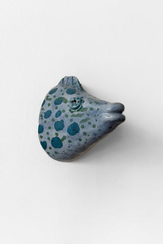 Ceramic fish-shaped object with blue and green pattern on a white background