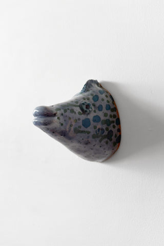 Ceramic fish head sculpture with blue speckled pattern on a white background