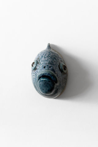 Speckled blue ceramic fish on a white background
