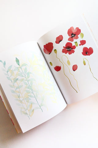 Open book with watercolor illustrations of red flowers and green leaves on a white background
