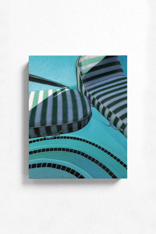 Striped pool chairs on a blue pool deck with tiled edge