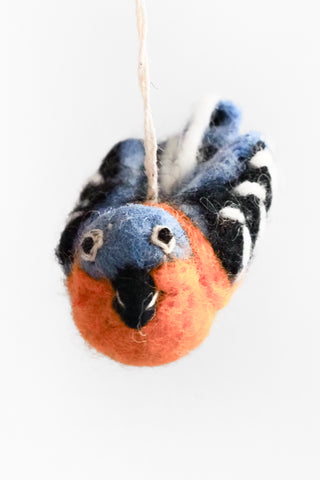 Felted bird ornament with orange breast and blue head on a white background