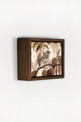 Square framed artwork of a bird on a branch with leaves on a white background