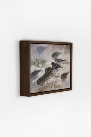 Framed artwork of birds on a snowy landscape on a white wall