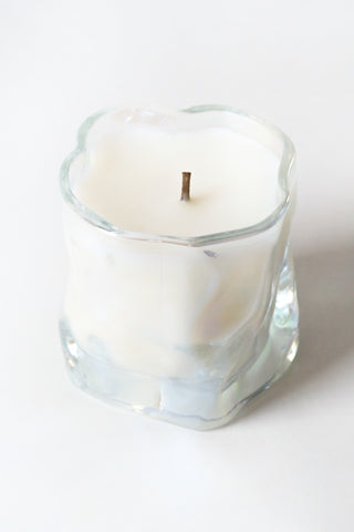 White candle in a clear glass holder on a white background