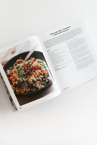 Open cookbook showing a dish with text on a white surface
