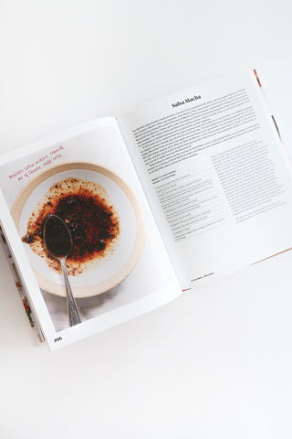 Open book with a plate of food and a spoon on a white surface