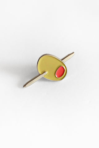 Olive pin with a gold border and red pit on a white background