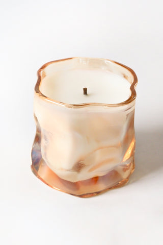 Candle in a glass container with a marbled design on a white background
