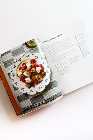 Open cookbook showing a page with a plate of salad on a white background