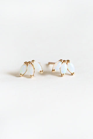 Pair of gold earrings with white stones on a light gray background