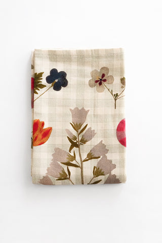 Folded floral patterned tea towel on a white background