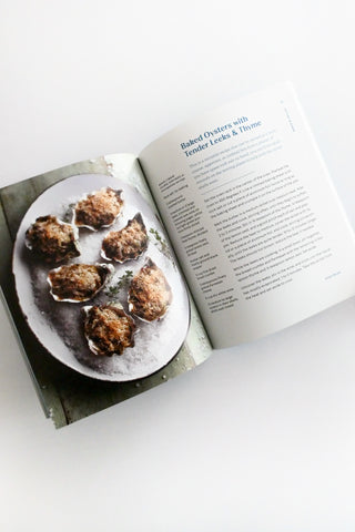 Open cookbook showing a plate of oysters on a white surface