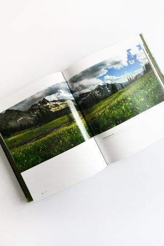Open book displaying scenic landscape with mountains and blue sky.