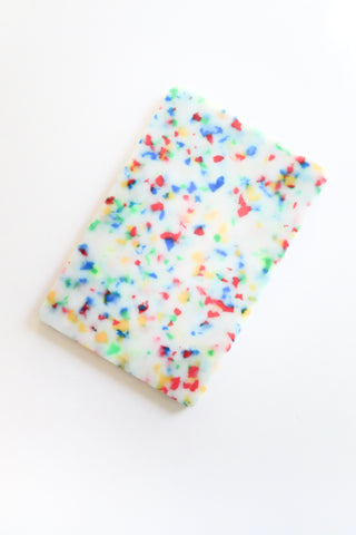 Cutting board with colorful sprinkles on a white background