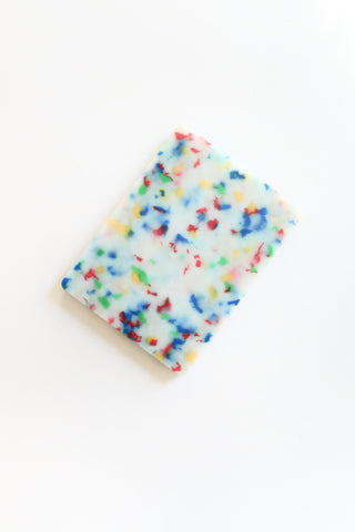 Cutting board with colorful sprinkles on a white background