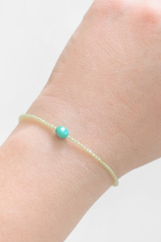 Turquoise beaded bracelet on a wrist against a white background