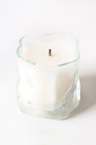 White candle in a glass container on a white background