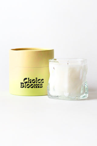 Glass candle and yellow container with 'Choice Blooms' text on a white background