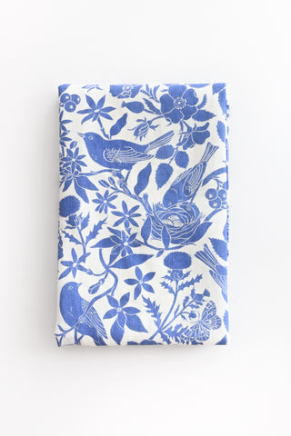 Folded tea towel with blue floral and bird pattern on a white background
