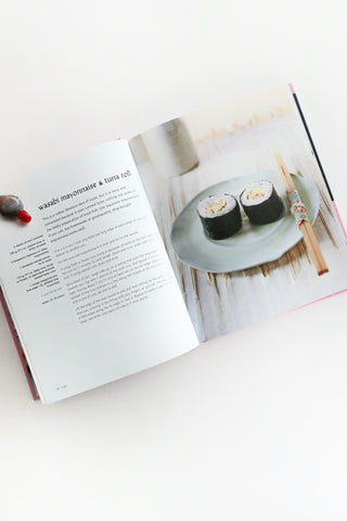 Open cookbook showing a page with sushi rolls on a plate