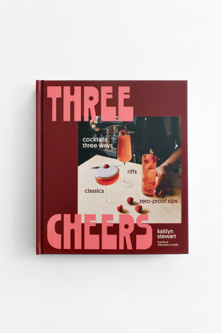 Book titled 'Three Cheers' with cocktail illustrations on a red background