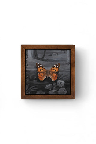 Framed artwork of two butterflies on a dark background with a wooden frame.