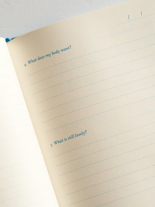 Notebook with lined pages and text prompts on a light background